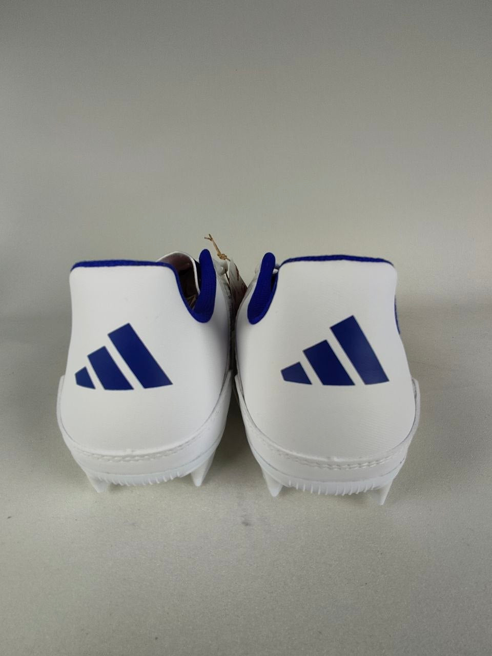 White Adidas F50 Club FxG with blue accents and Adidas logo on a gray background - Rear view @runinrain