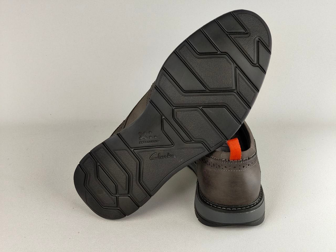 Brown leather shoe with black sole on a light gray background