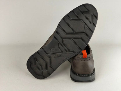 Brown leather shoe with black sole on a light gray background
