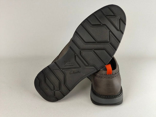 Brown leather shoe with black sole on a light gray background