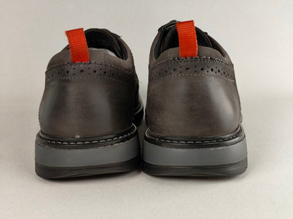Pair of dark brown shoes with red laces on a light gray background