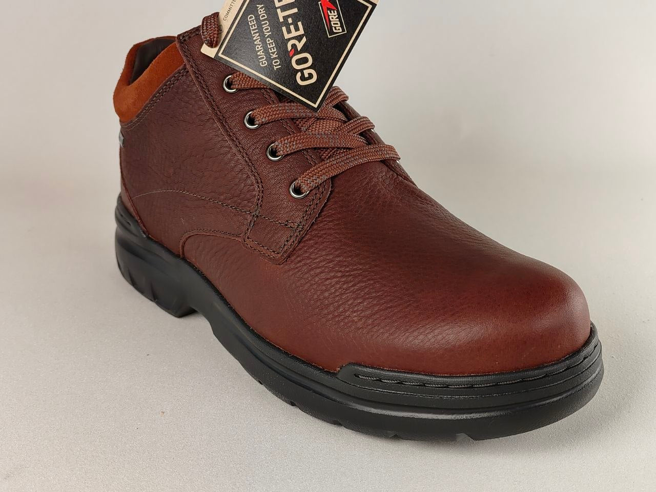 Brown leather shoe with a GORE-TEX label on a light gray background