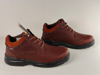 Pair of brown leather shoes with black soles on a light gray background
