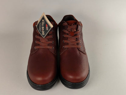 Pair of brown leather shoes with a Goretex tag on a light gray background