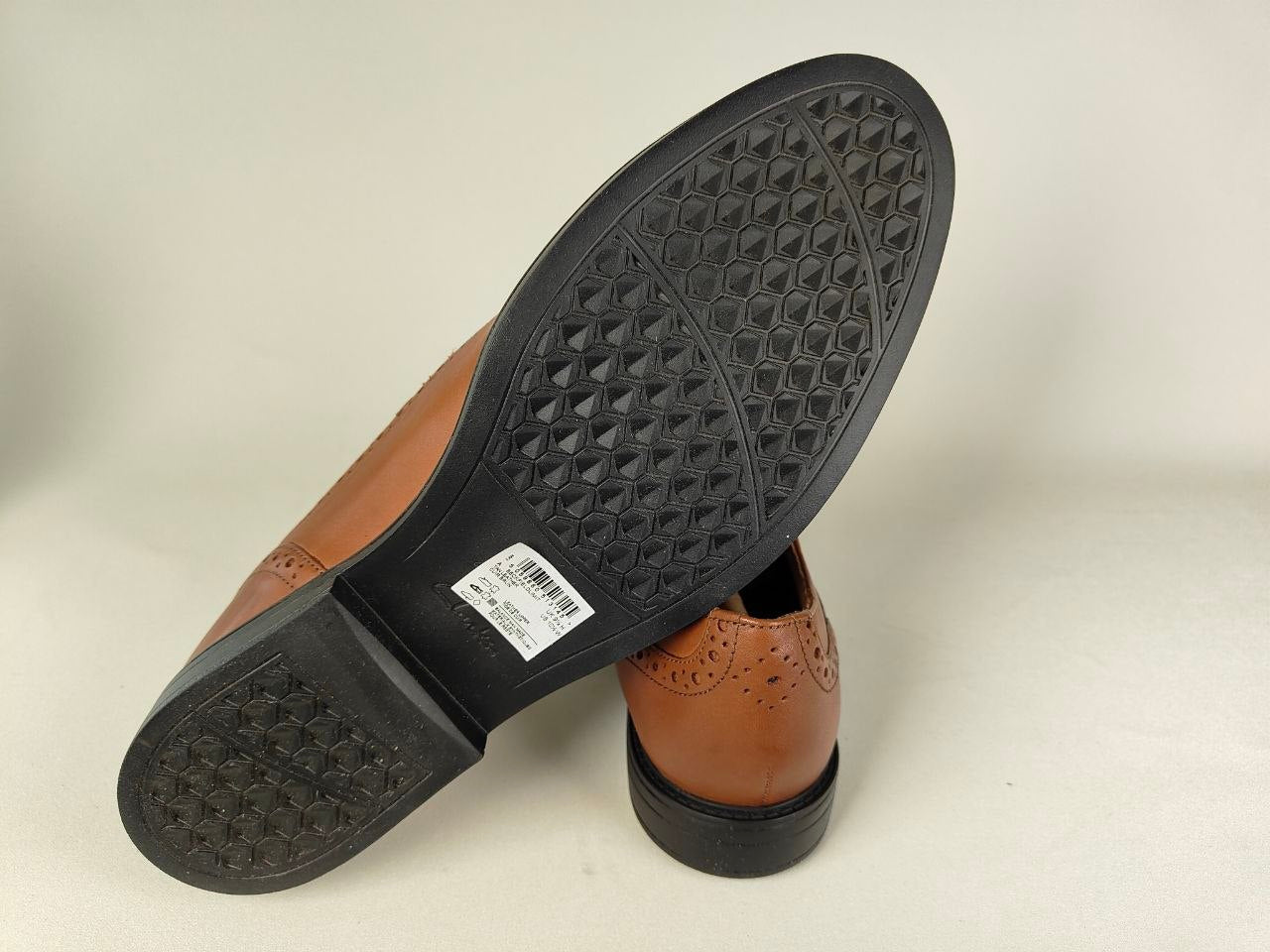 A Clarks Beckfield Limit Men's Tan Leather Wingtip Brogue shoe on another Clarks Beckfield Limit Men's Tan Leather Wingtip Brogue shoe on a light gray background – Sole View @RunInRain