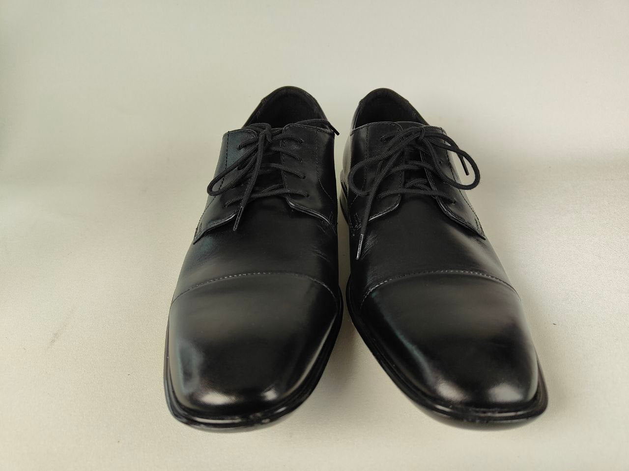 A pair of Clarks Bensley Cap Men's Black Leather Oxford shoes on a light gray background – front view @RunInRain