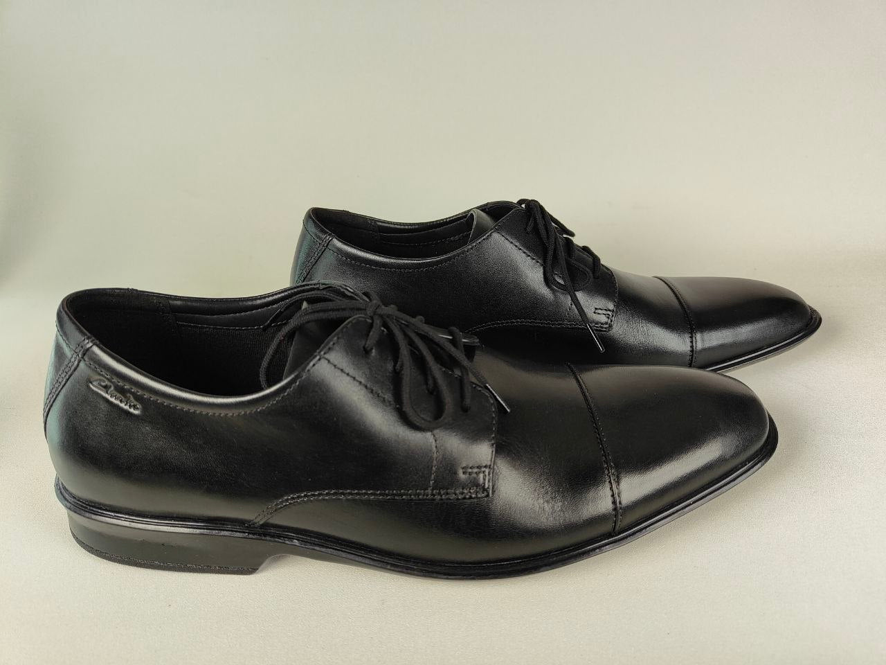 A pair of Clarks Bensley Cap Men's Black Leather Oxford on a beige background – side view @RunInRain 