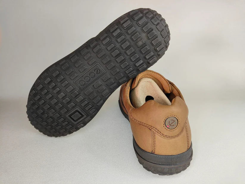 Brown shoe with black sole on a light gray background