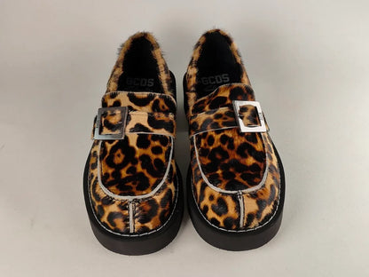 Pair of leopard print GCDS x Clarks 1 loafers with buckles on a light gray background