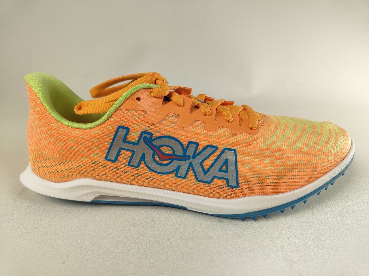 Orange HOKA Cielo X 2 MD track spikes with blue Hoka branding on a light gray background – Side View