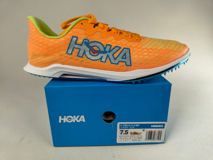 Orange HOKA Cielo X 2 MD track spikes with 'Hoka' branding on a blue shoe box - Side View