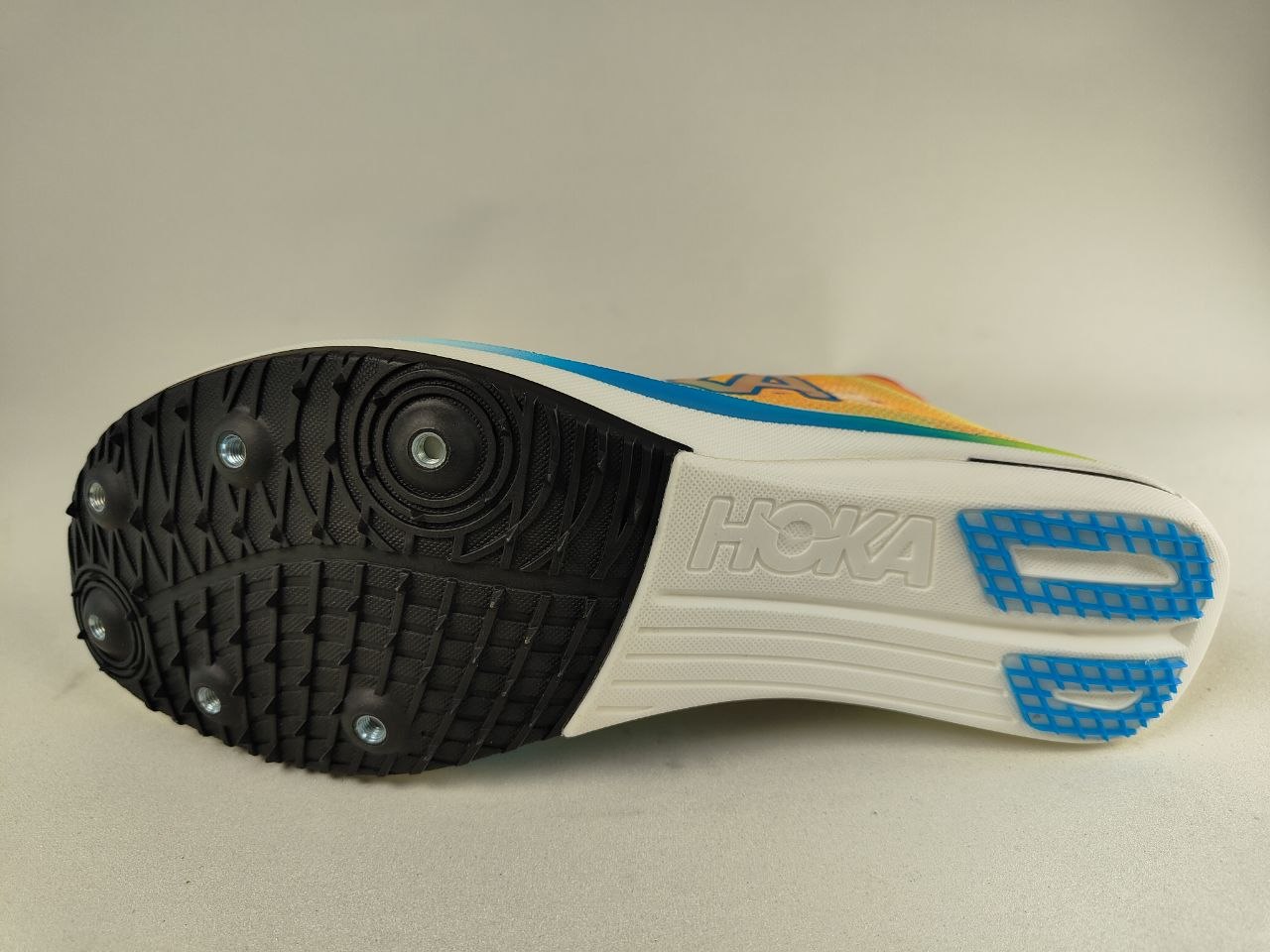 Close-up of a Hoka Cielo FlyX Carbon-Plated Track Spikes Solar Flare with 'Hoka' branding on a neutral background – Sole View hero shot @RunInRain