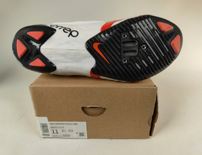 Sole of a Nike SuperRep Cycle 2 NN Indoor Cycling Shoe White/Black with red and black design on a cardboard box  on a light gray background – Sole detail View @RunInRain