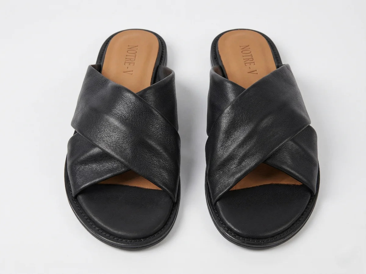 A pair of Notre-V Elegant Criss-Cross Black Leather Slides Women with open toe  and flat design on a light gray background – Front View @RunInRain