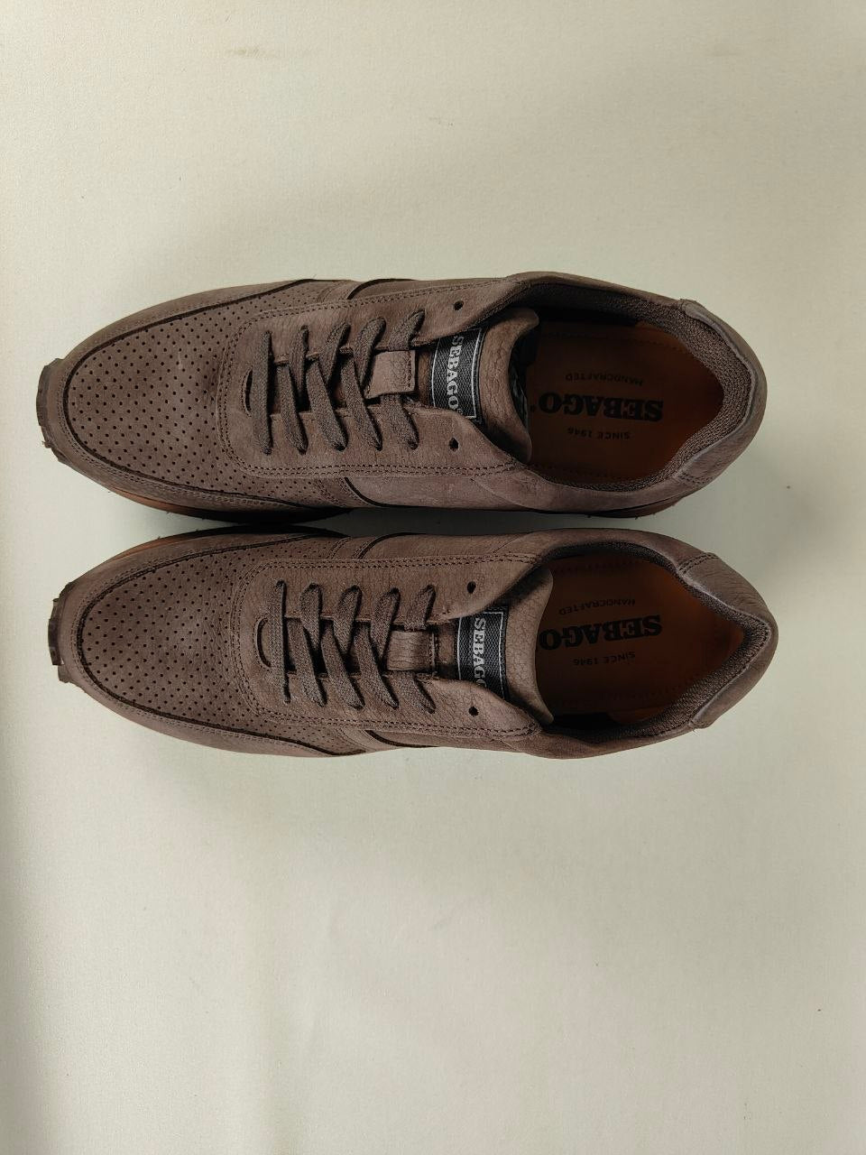 Pair of Sebago Jude NBK Dark Brown Sneakers on a light beige background